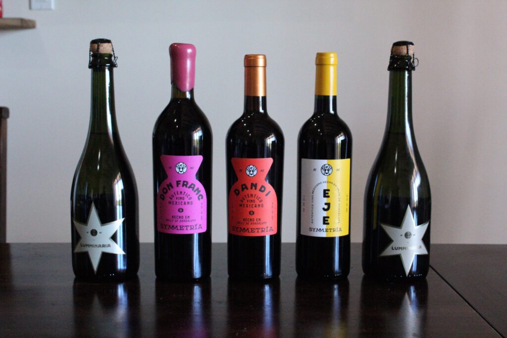 Symmetria’s Liquid Lineup: From bubbly Luminaria to bold reds like Don Franc, Dandi, and Eje—each bottle is a love letter to Baja, handcrafted with balance, heart, and zero shortcuts.