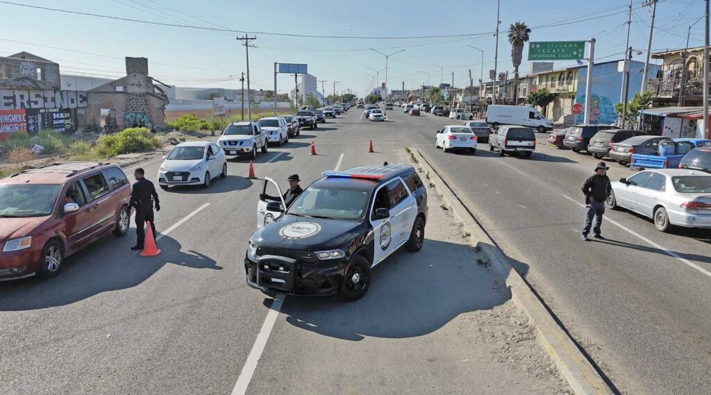 Checkpoint in action: Officers along the Tecate–Tijuana highway check cars for stolen vehicles and illegal goods—slowing traffic, speeding up justice.